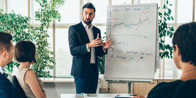Businessman presenting sales goals to colleagues in a meeting.