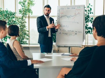 Businessman presenting financial growth chart to colleagues in a meeting.