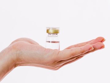 A small glass vial with clear liquid held in an open hand.