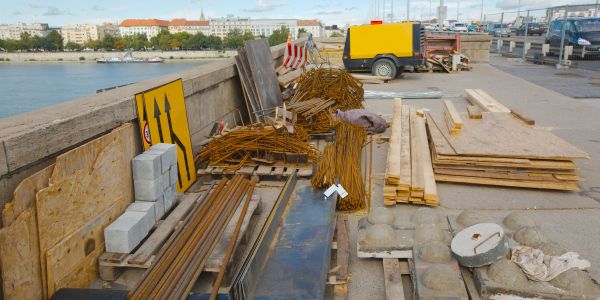 Construction materials and tools arranged on a bridge near water.