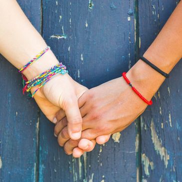 Queer gender neutral hands holding wearing bracelets blue wood background. PACT for couples. Austin