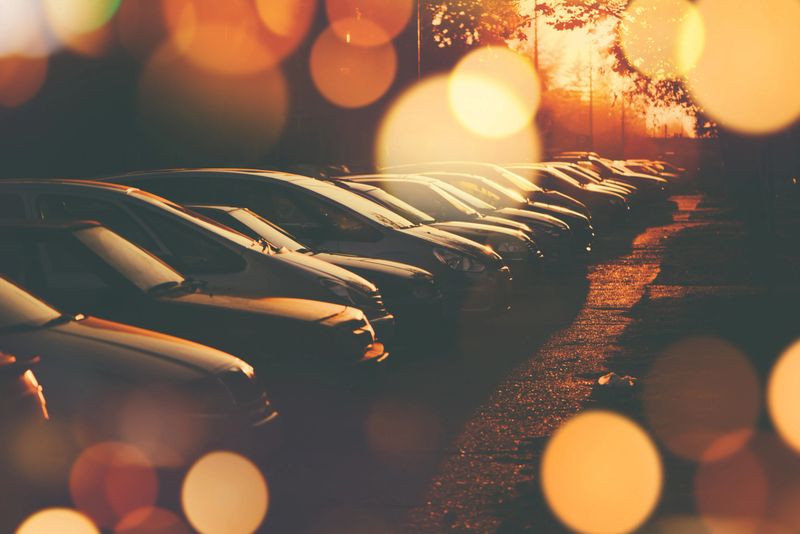 Rows of cars parked in residential district in sunset, retro toned image with lens flare and bokeh light, selective focus