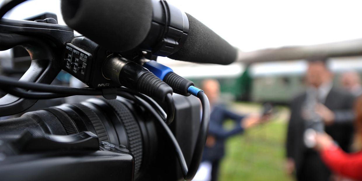 Close-up of a professional video camera during an outdoor interview.