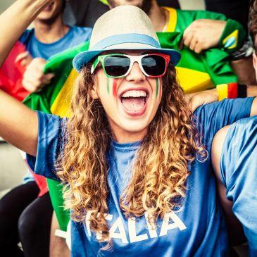 Excited fan with face paint and sunglasses cheering at a sports event.