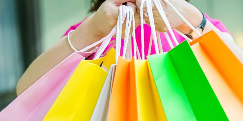 Smiling woman holding colorful shopping bags up close.
