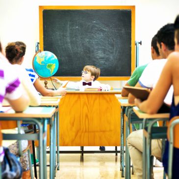 Young boy teaching a classroom with globe and blackboard.