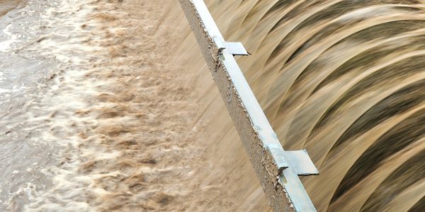 Turbid water flowing over a weir in a water treatment facility.