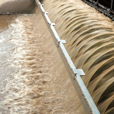 Turbid water flowing over a weir in a water treatment facility.