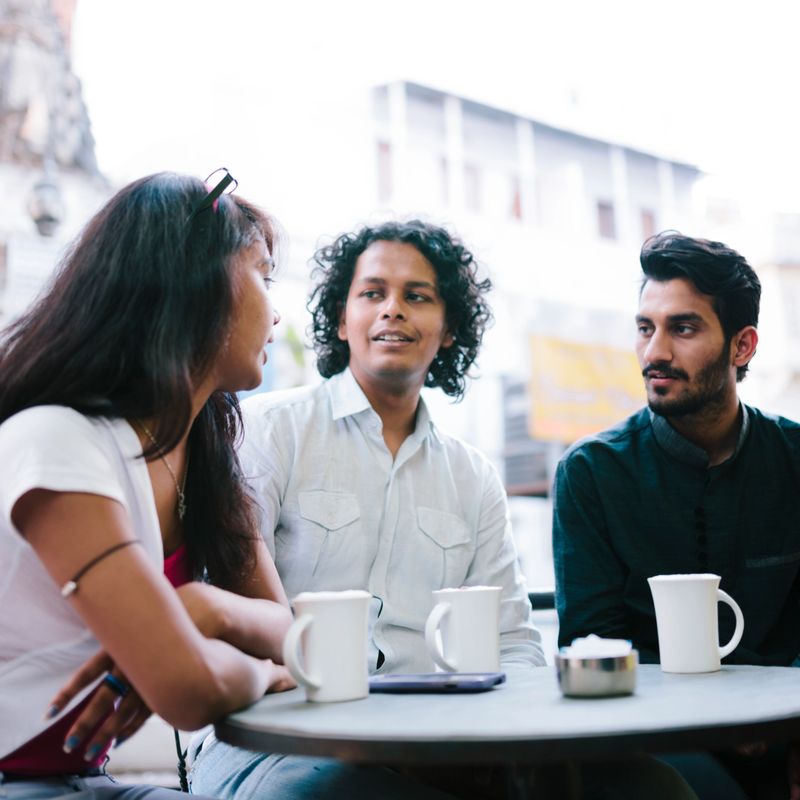 Three young adults socialise in a cafe, Udaipur, Rajasthan, India. 