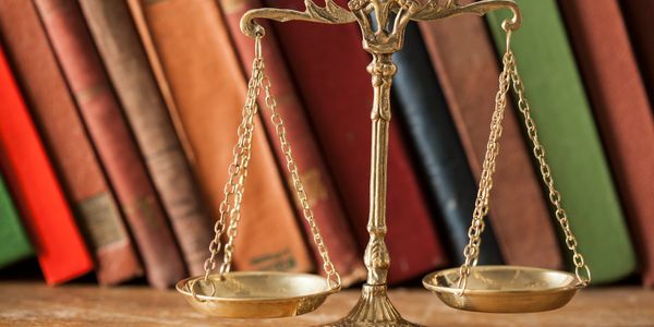 A golden balance scale with vintage books in the background.