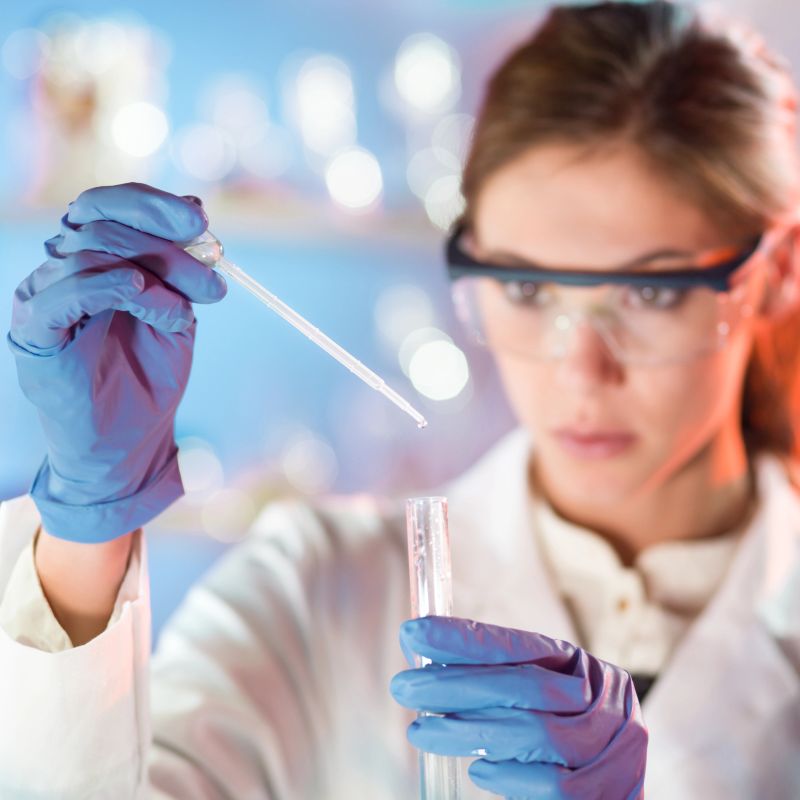 Focused young life science professional pipetting solution into the glass cuvette.