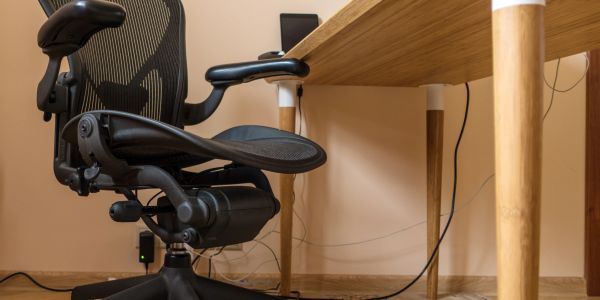 Ergonomic black office chair beside a wooden desk in a tidy workspace.