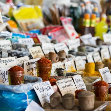 Colorful spices and herbs displayed with handwritten labels at a market stall.