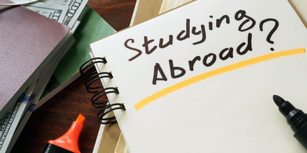 Notebook with 'Studying Abroad?' written, surrounded by study materials.