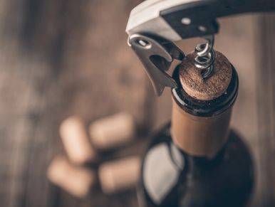 Wine bottle being opened with corkscrew.
