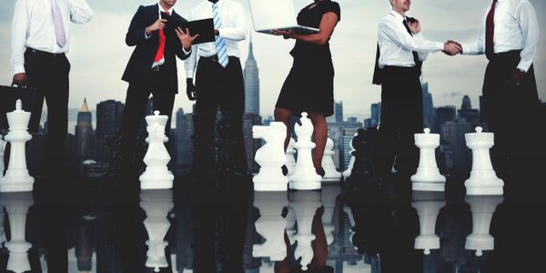 Business professionals strategizing on a giant chessboard with city skyline background.