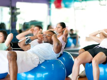 Group exercising on blue stability balls in a fitness class.