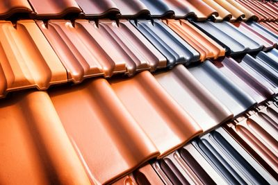 Close-up of multicolored ceramic roof tiles arranged in rows.