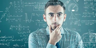 Young man deeply analyzing complex mathematical equations on a transparent board.