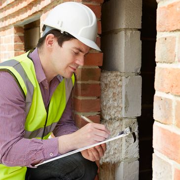 Construction worker inspecting and taking notes on a brick wall.