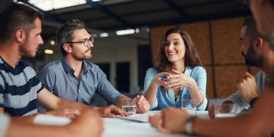 A woman leads a discussion with attentive colleagues in a modern meeting room.