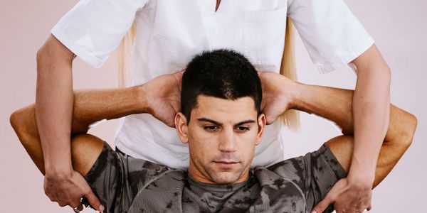 Therapist assisting a man with arm stretches for physical therapy.