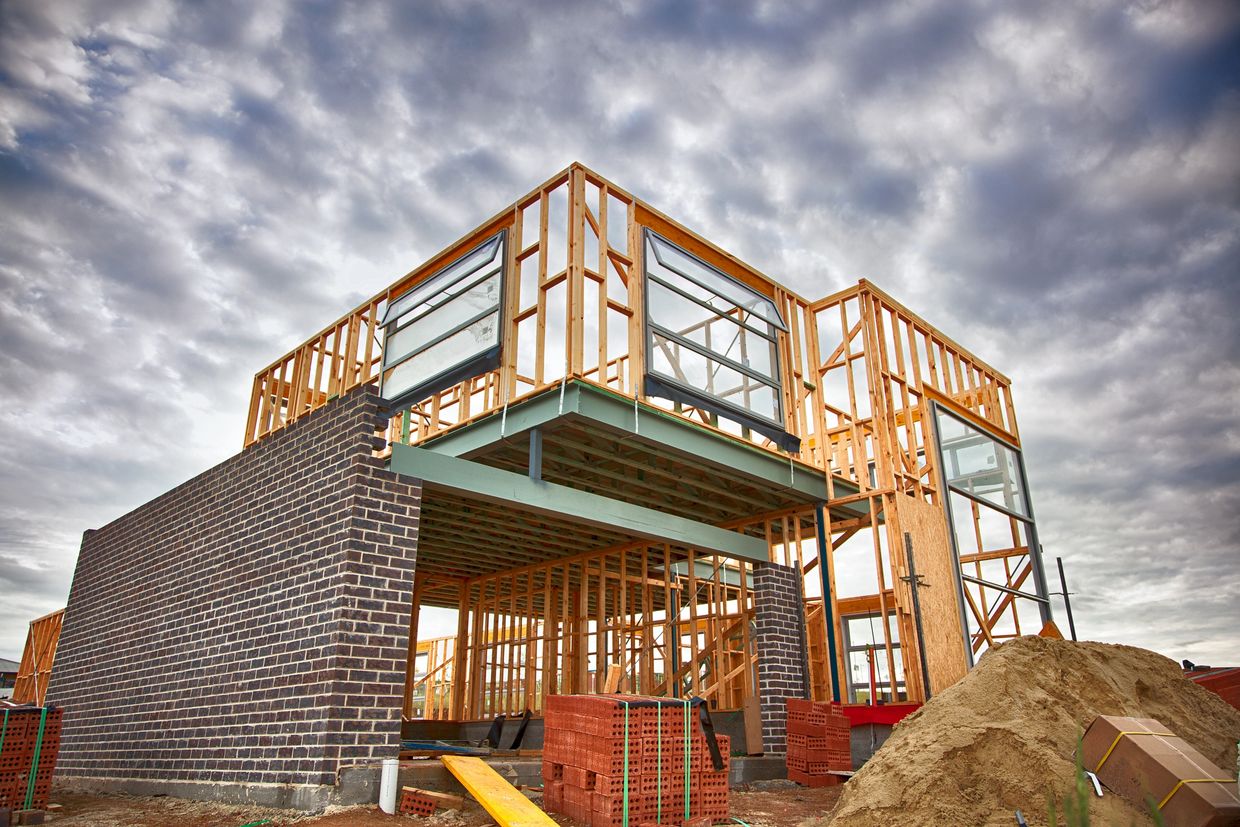Partially built house with wooden framing and brick walls under a cloudy sky.