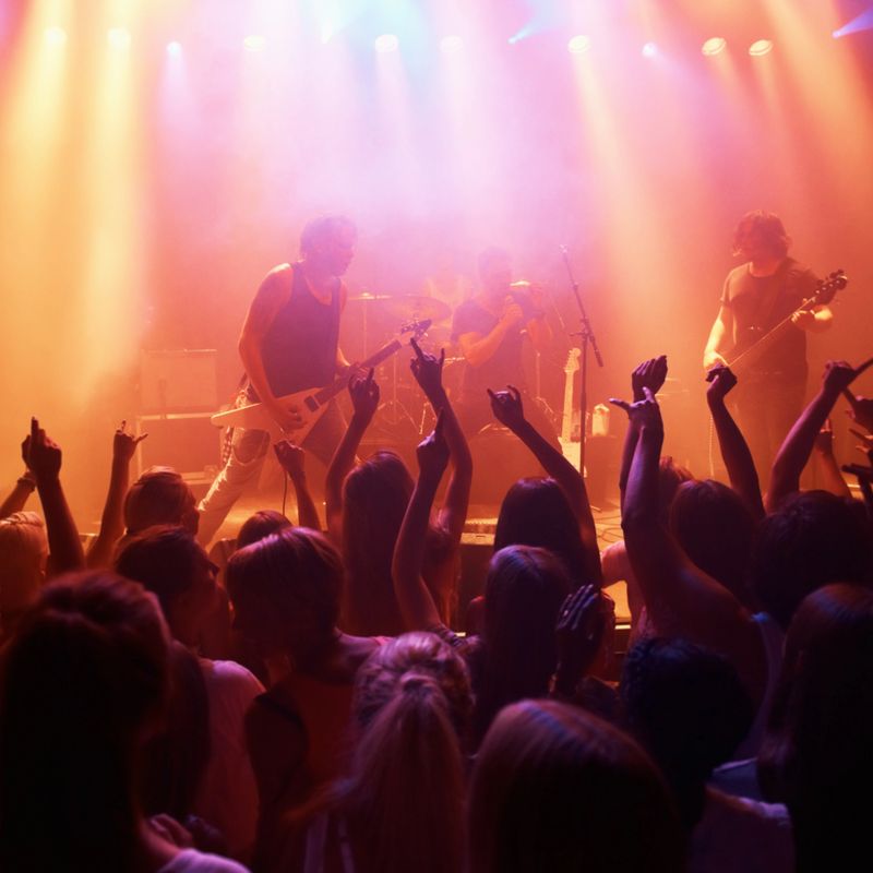 Rearview of a crowd at a music gig with their hands raised in the air. This concert was created for the sole purpose of this photo shoot, featuring 300 models and 3 live bands. All people in this shoot are model released.