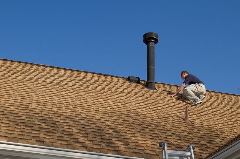 Inspector on the roof, inspecting a residential roof vent.