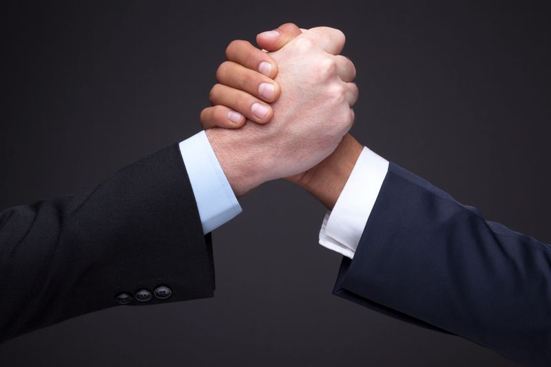 Two businessman making a wrist wrestling isolated on gray