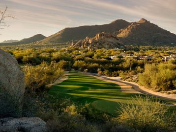 A golf course set in a desert landscape with rocky hills in the background.