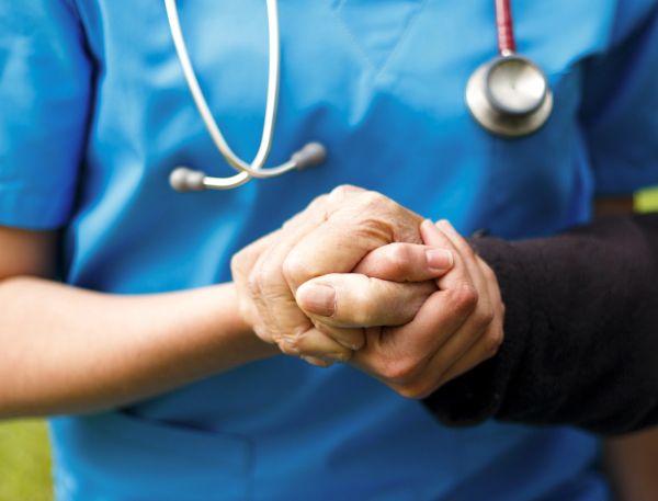 Healthcare worker holding an elderly person's hand.