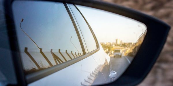 View of road and vehicles in a car's side mirror.