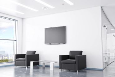 Modern waiting area with two black chairs and a TV.
