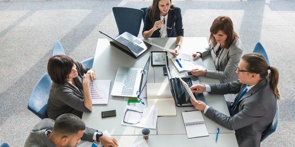 Business team collaborating around a table with laptops and charts.