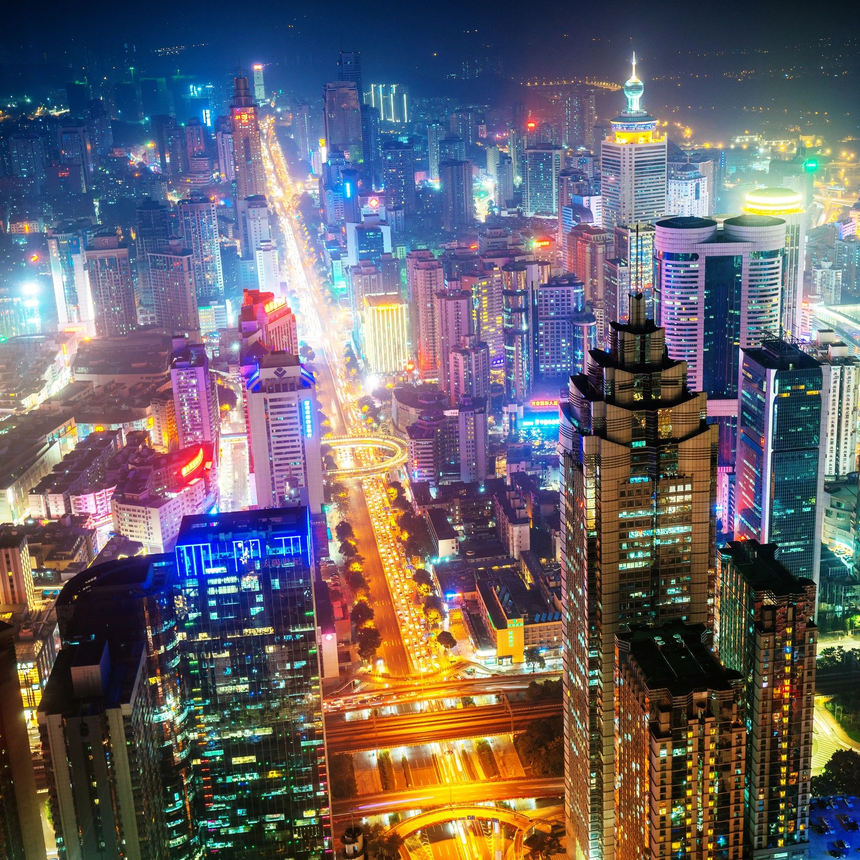 A vibrant cityscape illuminated at night with towering skyscrapers and busy streets.