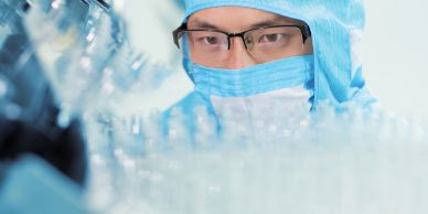 Scientist in protective gear working in a lab.