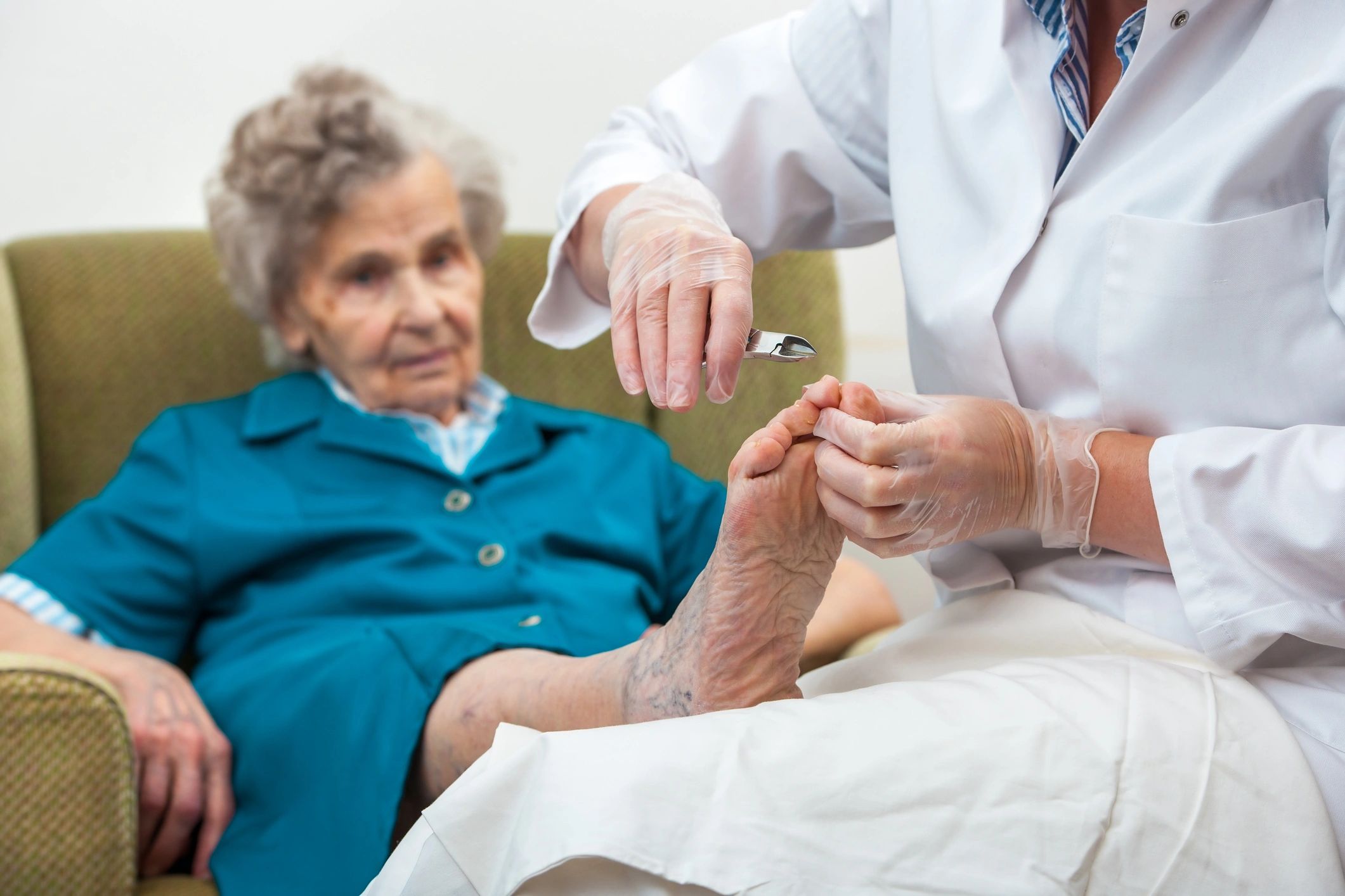 Clinician trimming the toenails of an older patient during a foot-care visit.