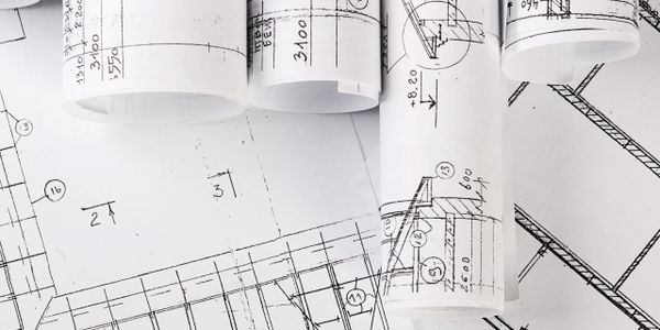 Rolled and flat architectural blueprints with detailed measurements and annotations.