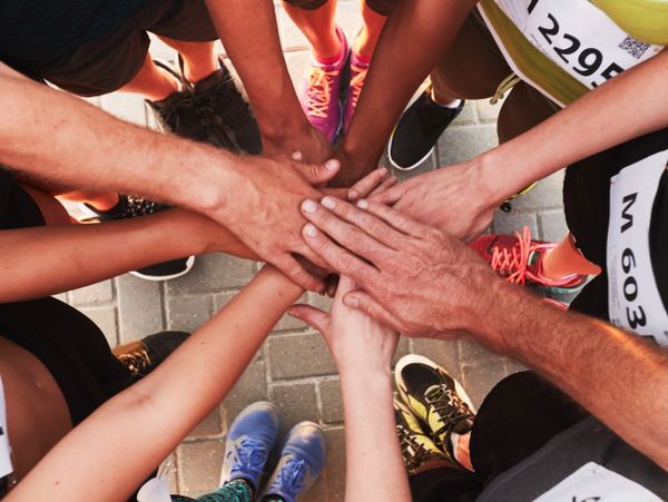 Runners join hands in a team huddle before a race.