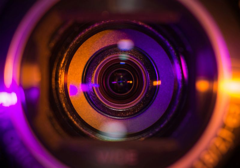 Video camera lens lit in orange and purple