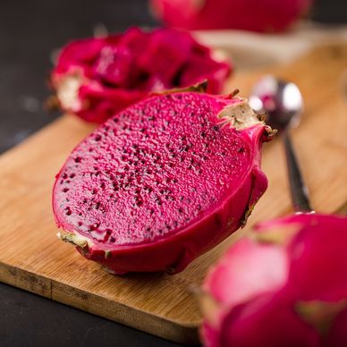 Close-up of a sliced red dragon fruit on a wooden board.