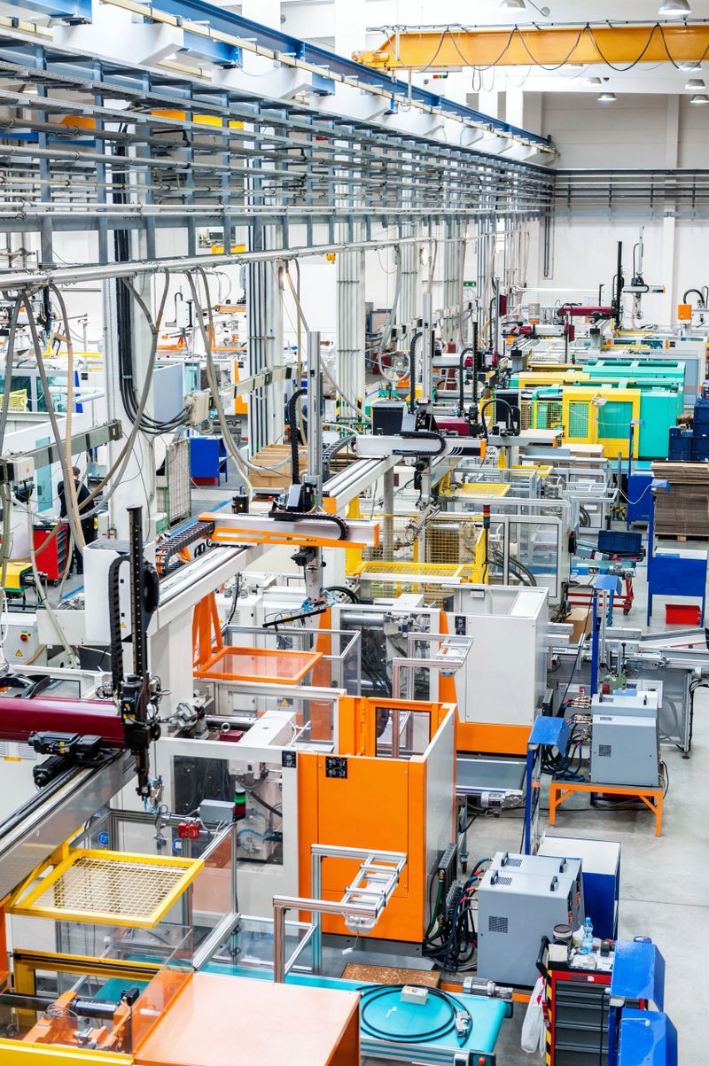 Vertical image of futuristic new factory producing plastic pieces for car industry. Factory modern interior where is placed a lot of robot machines which provide work for human, space for copy. Modern indoor hall for assembly.