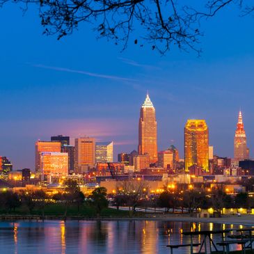 Cleveland city skyline illuminated at dusk with reflections in the water.