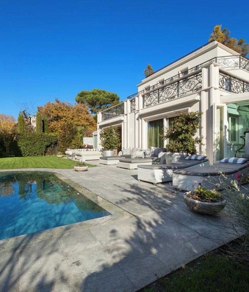 Architecture; beautiful house with pool, blue sky and lush garden