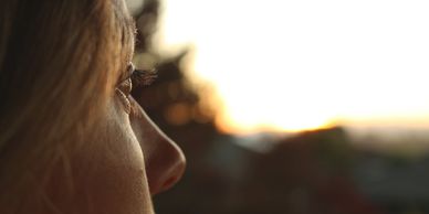 Close-up of a person gazing thoughtfully at a sunset.