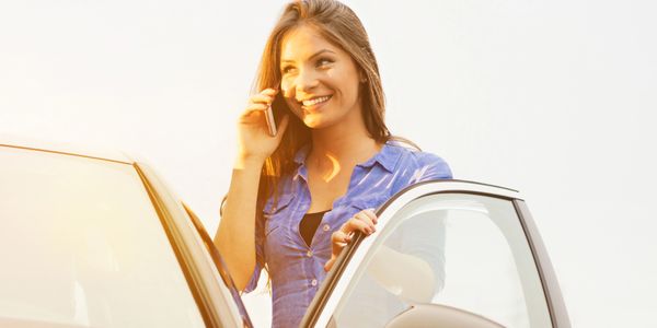 woman talk On the mobile In front of the car