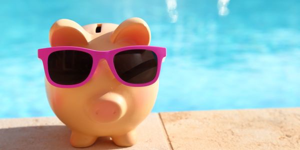 Piggy bank wearing pink sunglasses by a pool on a sunny day.