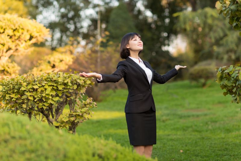 chinese female white-collar workers standing on the lawn of the park, enjoy the fresh air
