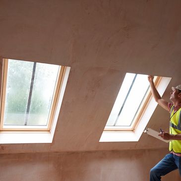 Worker inspecting skylights in attic.